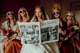 Bride and bridesmaids in heart sunglasses reading The Norms wedding newspaper